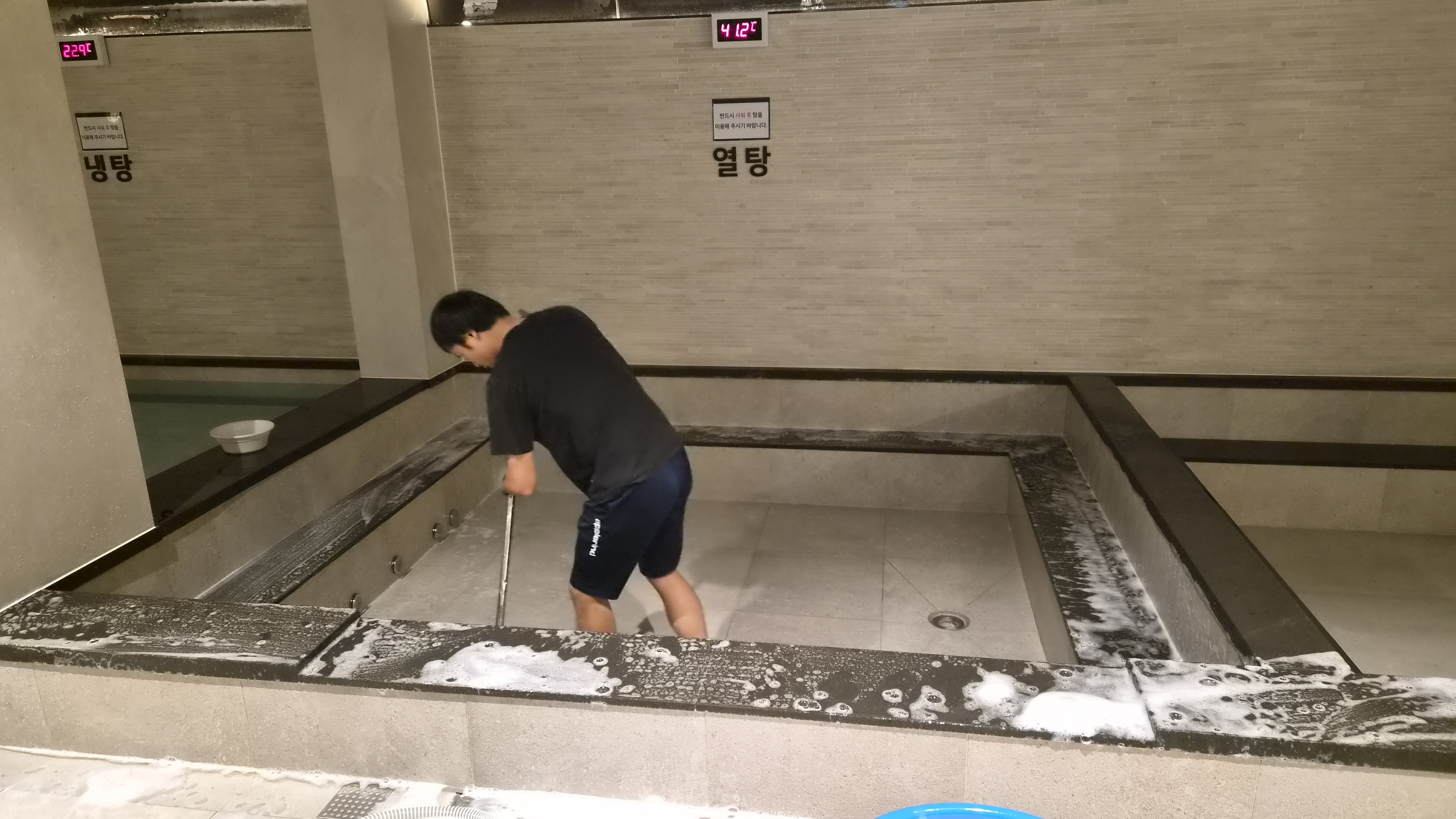 작업자가 욕탕 안쪽과 테두리를 직접 세척하는 모습